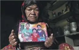  ??  ?? SUBITRA BHANDARI holds a photo of Tejendra with his daughter and wife. Tejendra died in a 2015 car accident while working in Saudi Arabia.