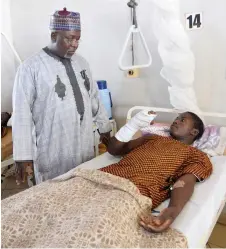  ?? ?? Cummunity leader and Chairman of Kanam district Yusuf Dayyabu Garga (standing) tends to Yahaya Musa, a survivor of bandit attacks, at the Jos University Teaching Hospital where Musa is receiving treatment for injuries in Jos.