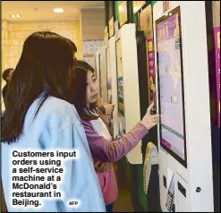  ?? AFP ?? Customers input orders using a self-service machine at a McDonald’s restaurant in Beijing.