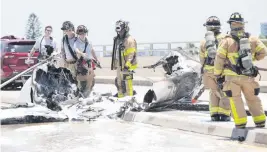  ?? ANDREW ULOZA For the Miami Herald ?? Firefighte­rs work at the scene of a plane crash at the Haulover Inlet Bridge that killed one person and injured five others, Miami-Dade Fire Rescue said.