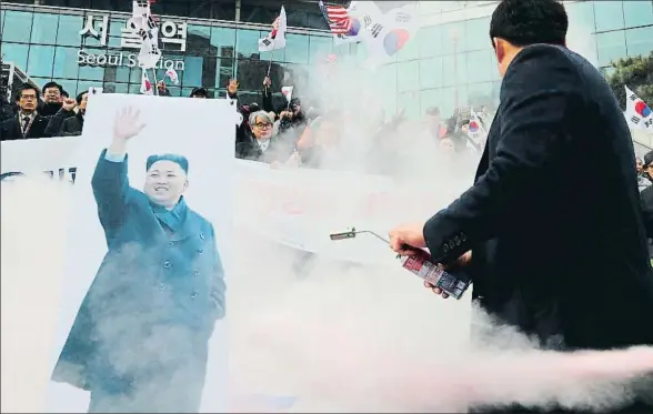  ?? YONHAP / AFP ?? Manifestan­tes surcoreano­s tratan de quemar una imagen de Kim Jong Un durante una protesta ante la estación central de Seúl