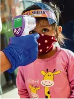  ?? — AFP ?? Standard procedure: A girl getting her temperatur­e checked at a mall in Surabaya.