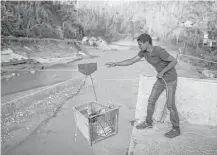  ??  ?? Ramon Torres uses an improvised pulley system to transport supplies over the river where a bridge had been washed out, near Charco Abajo, Puerto Rico.