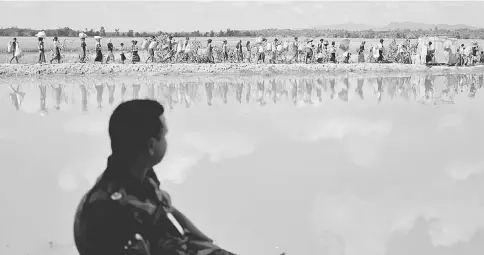  ??  ?? A Bangladesh­i border guard watches as Rohingya refugees who fled from Myanmar walk back, in Palang Khali, Bangladesh. — Reuters photo