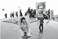  ?? Associated Press ?? ■ Two boys hold up posters of Iranian Supreme Leader Ayatollah Ali Khamenei, right, and late revolution­ary founder Ayatollah Khomeini, left, on Monday during a rally marking the 40th anniversar­y of the 1979 Islamic Revolution in Tehran, Iran.