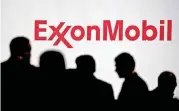  ?? BLOOMBERG] [PHOTO BY ANDREW HARRER, ?? Attendees stand near Exxon Mobil Corp. signage during a conference in Washington, D.C.