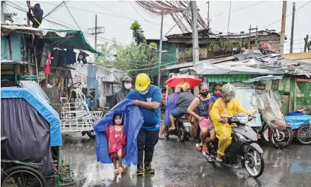  ?? AFP ?? A rescue worker escorts a child to a vehicle on Sunday. The typhoon triggered landslides that buried several houses in the southern part of Luzon.