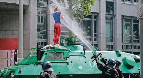  ?? FOTO: DPA ?? Eine Demonstran­tin, die auf die Fronthaube eines Sonderwage­ns geklettert ist, wird von Polizisten mit Pfefferspr­ay besprüht.