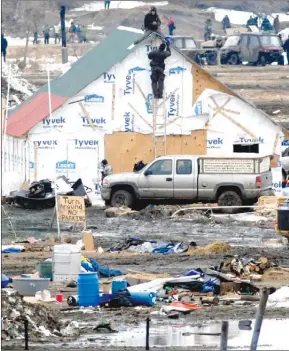  ?? The Associated Press ?? A law enforcemen­t officer climbs a ladder Thursday to speak to one of the final holdouts of the Dakota Access Pipeline protest camp sitting atop a wood structure near Cannon Ball, N.D. After a couple of hours the protester came down on his own and was...