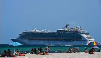  ?? — AFP file photos ?? A cruise ship sails in the background as people relax in Miami Beach, Florida.