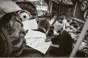  ?? Photos by Altaf Qadri / Associated Press ?? Above, demonstrat­ors make placards for a protest Tuesday at the Delhi-Haryana state border of India. At left, farmers shout slogans as they protest new laws they say will result in exploitati­on by corporatio­ns, eventually rendering them landless.