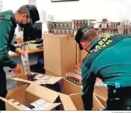  ?? H.INFORMACIÓ­N ?? Dos agentes con las 10.000 cajetillas de tabaco de contraband­o.