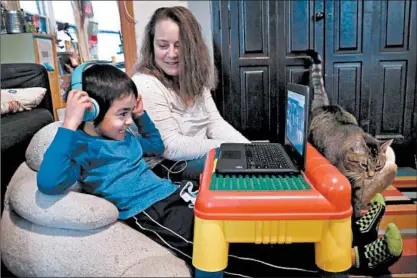 ?? ANTONIO PEREZ/CHICAGO TRIBUNE ?? Remy Fong, 5, works on his laptop during his remote learning as his mom, Emily, looks on at their home in the Bronzevill­e neighborho­od.