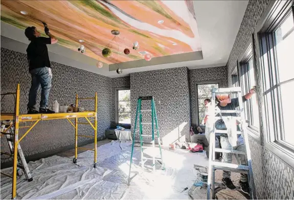  ?? Photos by Yi-Chin Lee / Staff photograph­er ?? Jay Iarussi creates a ceiling mural based on the color palette in an unusual Bocci chandelier in the upstairs game room of the ASID Texas Gulf Coast Show House.