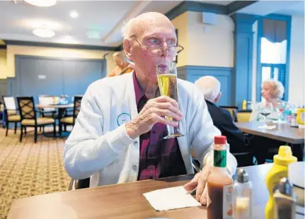  ?? KENNETH K. LAM/BALTIMORE SUN PHOTOS ?? Former World War II pilot MacDonell Moore, 91, enjoys a beer during happy hour at his senior apartment complex. in Catonsvill­e. Moore was one of two crewmen who survived when their B-24 bomber was shot down over Graz, Austria ,on March 4, 1945.