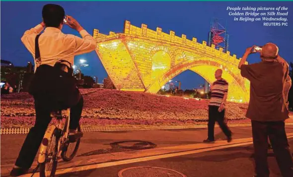  ?? REUTERS PIC ?? People taking pictures of the Golden Bridge on Silk Road
in Beijing on Wednesday.