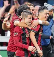  ??  ?? Atlanta United midfielder Miguel Almiron (right) is mobbed by teammates after scoring to give Atlanta a 2-0 lead in the second half Sunday.