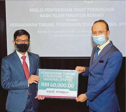  ?? PIC BY SAIFULLIZA­N TAMADI ?? Bank Islam Malaysia Bhd chief executive officer Mohd Muazzam Mohamed (left) handing over business tithe worth RM40,000 to the National Higher Education Fund Corporatio­n, which is represente­d by its chief executive officer, Ahmad Dasuki Abdul Majid, at a handover ceremony in Kuala Lumpur yesterday.