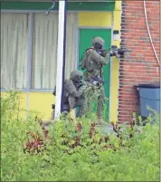  ?? Daniel Bell ?? Two members of the SWAT team post up next to a hotel building during a standoff with a suspect on Tuesday.