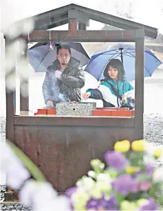  ?? — AFP photo ?? People pray in front of the former Okawa elementary school in Ishinomaki, Miyagi Prefecture.