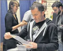  ?? KENN OLIVER/THE TELEGRAM ?? Colin Fewer reads up on one of the 128 different beer available at the Craft Beer Attraction. The competitiv­e runner and amateur brewmaster developed an appreciati­on for craft beer on trips outside the province for road races.