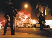  ?? Kent Nishimura Los Angeles Times ?? MEMBERS OF law enforcemen­t patrol the Fairfax district, with structures ablaze, after protests erupted over the killing of George Floyd in May.