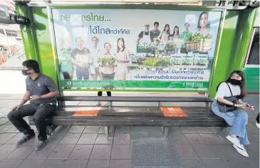  ?? PORNPROM SATRABHAYA ?? Two passengers yesterday keep their distance to help curb the spread of Covid-19 while they wait for public buses in the Victory Monument area in Bangkok, one of the 28 red-zone provinces.