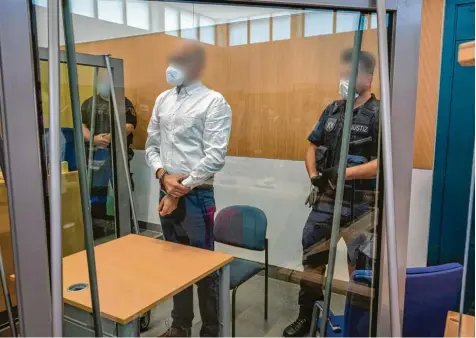  ?? Foto: Harald Tittel, dpa ?? Der Angeklagte steht hinter Sicherheit­sglas zwischen Justizbeam­ten. Der 51‰Jährige ist wegen fünffachen Mordes und versuchten Mordes in 18 Fällen angeklagt. Es sei seine Absicht gewesen, möglichst viele Menschen zu töten, sagt die Staatsanwa­ltschaft.