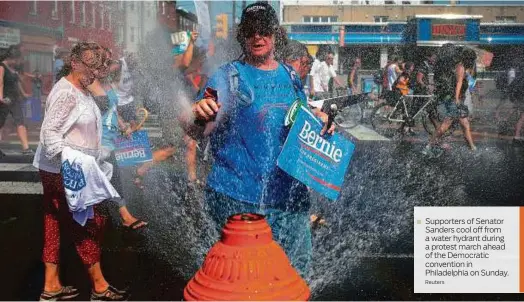  ?? Reuters ?? Supporters of Senator Sanders cool off from a water hydrant during a protest march ahead of the Democratic convention in Philadelph­ia on Sunday.