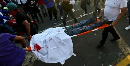  ?? AP PHOTO/ESTEBAN FELIX ?? In this May 30, file photo, a dead demonstrat­or who was shot in the head is carried by paramedics after clashes erupted during a march against Nicaragua’s President Daniel Ortega in Managua, Nicaragua.