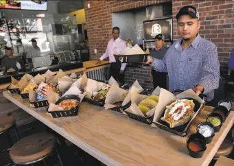  ?? Photos by Michael Macor / The Chronicle ?? Manager Oscar Garcia displays menu items at the Taco Bell Cantina that opened this week at Third and Townsend streets in San Francisco. The only other Taco Bell employing the Cantina concept is in Chicago’s Wicker Park.