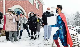  ??  ?? El farmacéuti­co
Mayank Amin llega vestido con un disfraz de superhéroe durante una nevada con una caja de vacunas contra el Covid-19