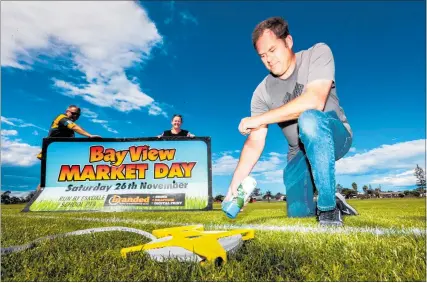  ?? PHOTO / PAUL TAYLOR ?? Eskdale school principal Tristan Cheer continues marking Petane Domain for Saturday’s Bay View Market sites, while Brett and Michelle Barnes recover a sign skittled by winds gusting up to 30 knots.