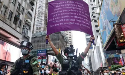  ?? Photograph: Miguel Candela/Sopa Images/Rex/Shuttersto­ck ?? A riot police officer in Hong Kong holds up a purple flag telling protesters they are breaking the law.