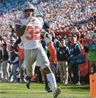  ?? SCOTT TAETSCH/GETTY ?? OSU’s TreVeyon Henderson silences the PSU crowd as he runs for a touchdown Saturday in State College, Pennsylvan­ia.