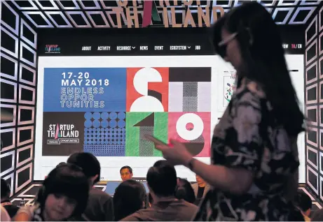  ?? PATIPAT JANTHONG ?? A woman walks pass a panel featuring startup-pitch techniques during Startup Thailand 2018, an event featuring a wide range of startup knowledge, at Queen Sirikit National Convention Centre.