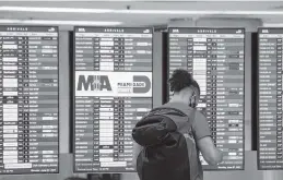 ?? DANIEL A. VARELA dvarela@miamiheral­d.com ?? A traveler checks the time of his connecting flight in the arrivals terminal at Miami Internatio­nal Airport.