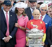  ?? AP/JULIO CORTEZ ?? Owner Kenny Troutt (far left) and trainer Bob Baffert (right) look on as jockey Mike Smith holds the August Belmont trophy after riding Justify to victory Saturday.