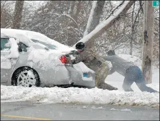  ?? TIM VIZER/AP ?? Two men strain as they push a car out of a snow pile it was stuck in after sliding sideways Saturday in Belleville, Ill.