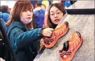  ?? ZOU HONG / CHINA DAILY ?? Visitors check shoes at the ISPO outdoor sports expo in Beijing in February.