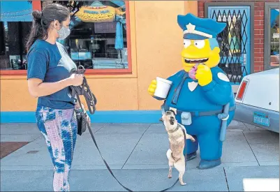 ??  ?? Chief Wiggum from The Simpsons enjoys a donut as Universal Studios theme park prepares to reopen in Los Angeles