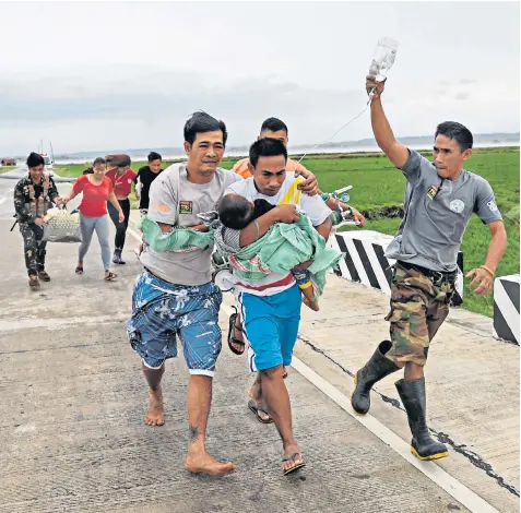  ??  ?? Soldiers assist a family by carrying their sick child to a waiting government vehicle after their ambulance failed to make it through a blocked road in Baggao, Cagayan province