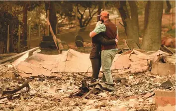  ?? AFP ?? Chris and Nancy Brown embrace while looking over the remains of their burnt residence after the Camp Fire tore through the region in Paradise, California, on Monday.