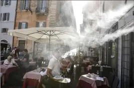  ?? RICCARDO DE LUCA — THE ASSOCIATED PRESS ?? On July 31, a fan sprays water mist as customers sit outside a cafe in downtown Rome during a heat wave with temperatur­es over 34 Celsius (104 Fahrenheit).