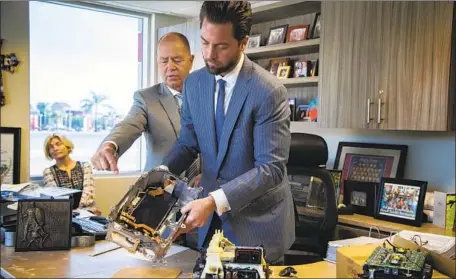  ?? Gina Ferazzi Los Angeles Times ?? ROGER HOGAN, left, Toyota of Claremont owner, and his son Kyle Hogan, a manager, show a defective power inverter from a 2012 Prius.