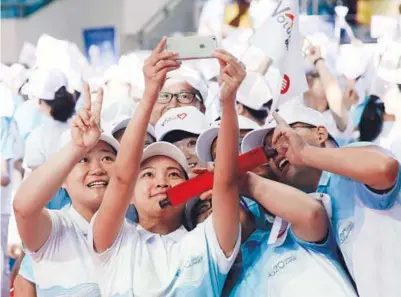  ?? WANG ZHUANGFEI / CHINA DAILY ?? A group of volunteers named
Xiaoqinghe, literally Little Green Lotus, put themselves in the picture before taking up duties at the summit.