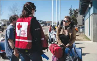  ?? Canadian Press photo ?? Red Cross volunteer Karen Wyonzek (left) registers displaced person Shanna Skinner at an evacuee registrati­on centre at an ice arena in the Thickwood Heights neighbourh­ood of Fort McMurray on Tuesday.