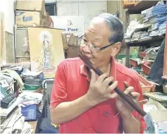  ??  ?? Lai playing the flute in his crowded shop filled with all kinds of supplies.