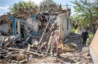  ?? AFP/VNA Photo ?? A couple brings their luggage out of their destroyed house in the village of Vilkhivka, near the eastern city of Kharkiv, on Saturday, on the 80th day of the Russian 'military operation' in Ukraine.