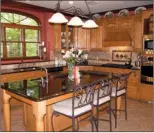  ??  ?? The spacious kitchen offers wood cabinetry, granite counters and stainless-steel appliances.